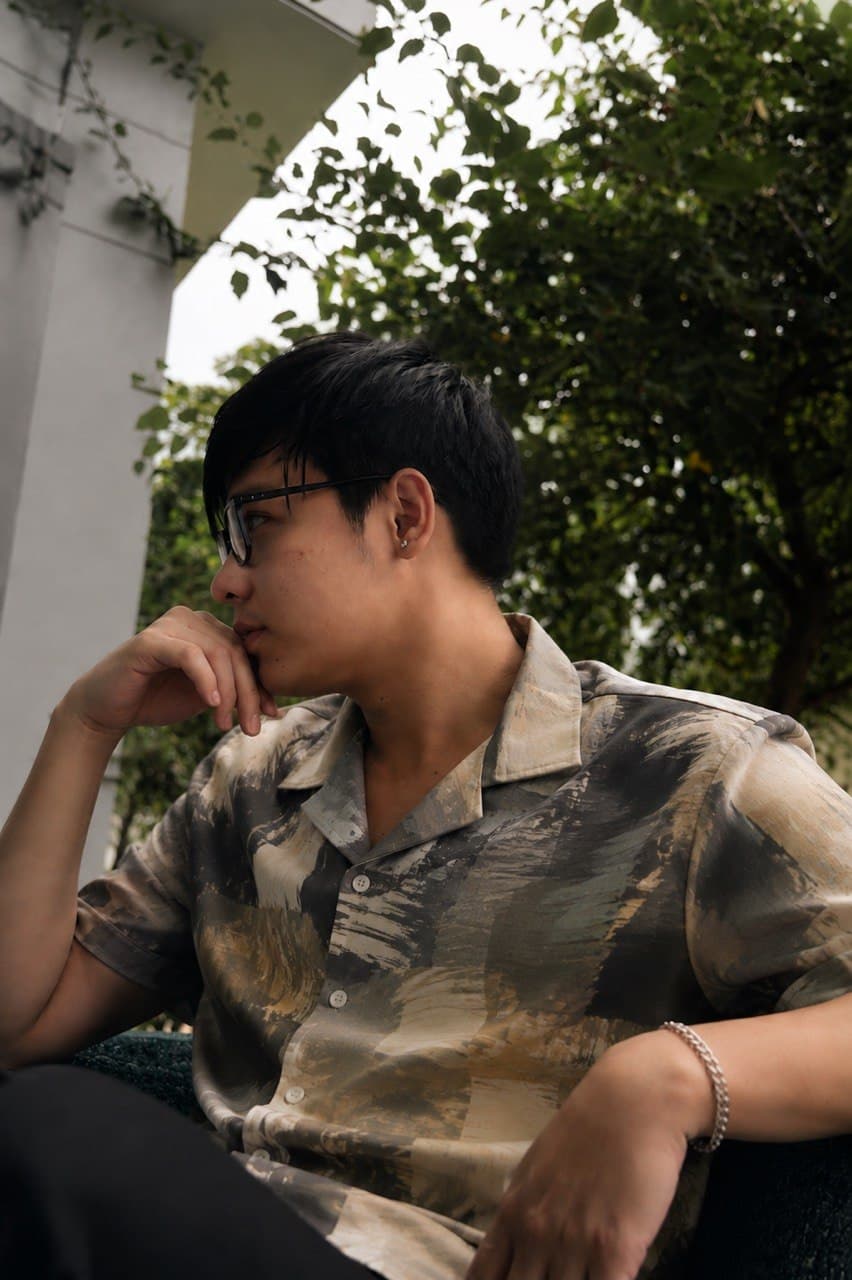 Khoa in a patterned shirt, seated outdoors in profile
